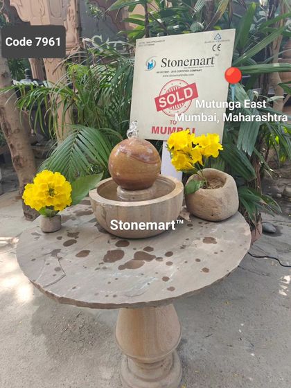 A small rainbow sandstone sphere fountain, sold to a client in Mumbai. It is displayed here on one of our stone tables, showing how well our different products complement each other.