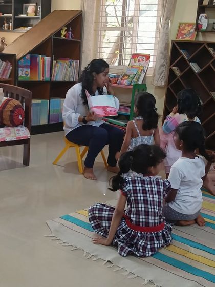 The storyteller shows the children a book about the life cycle of a butterfly, turning a science lesson into a magical story.