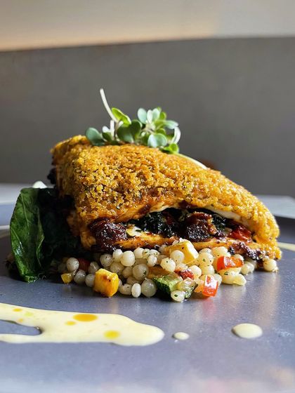 A side view of the cottage cheese steak, showing the layers of couscous, the thick steak, and the creamy jalapeño cheese fondue.