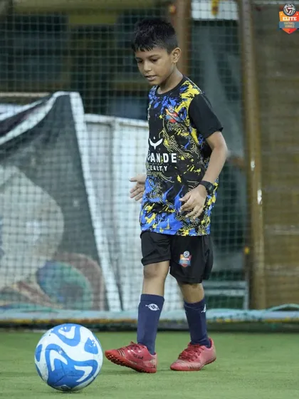A young player practices his ball control, keeping the ball close while staying balanced. Mastering this skill is fundamental to becoming a confident footballer.