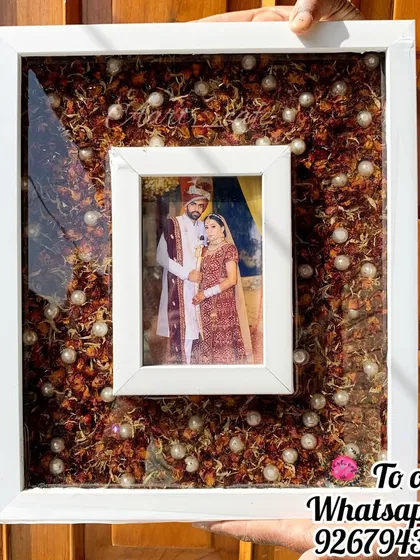 This elegant white frame offers a modern and clean look for varmala preservation. The floating photo design in the center is surrounded by a bed of preserved flowers and pearls, creating a beautiful contrast.