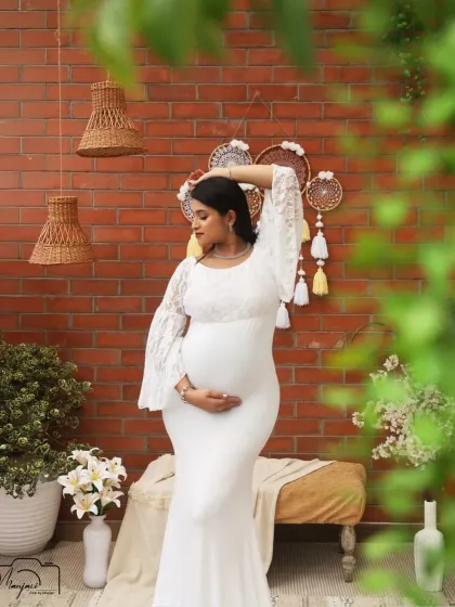 A stunning solo portrait in a white bodycon gown. The lace bell sleeves add a touch of boho elegance, and the pose highlights her beautiful bump.