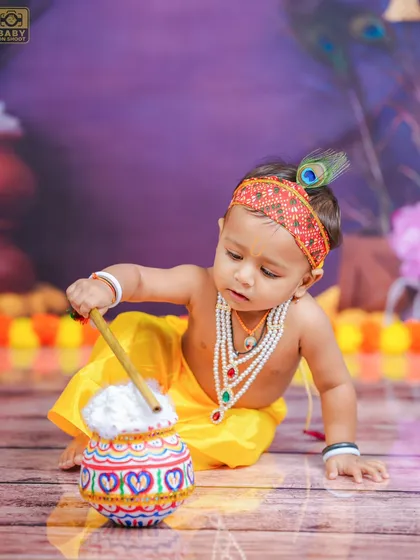 Focused on his pot of butter, this little Krishna is lost in his own world. These are the candid moments that families cherish forever.