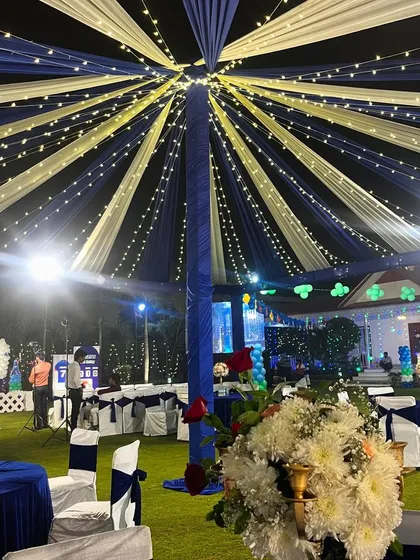 An outdoor tent setup with a canopy of blue and white drapes and fairy lights, creating a starry night effect.