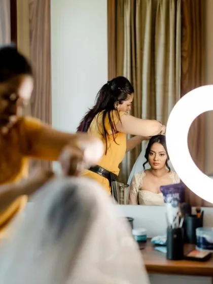 Behind-the-scenes moments from a beautiful Goa wedding. These shots show the careful process of creating the perfect winged liner and soft blush, ensuring the bride feels her best.