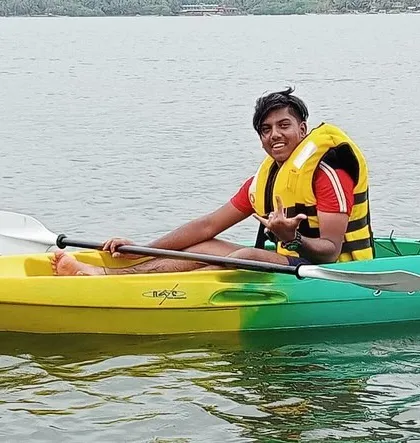A camper gives a thumbs-up from his kayak, enjoying the individual paddling experience at Karwar.