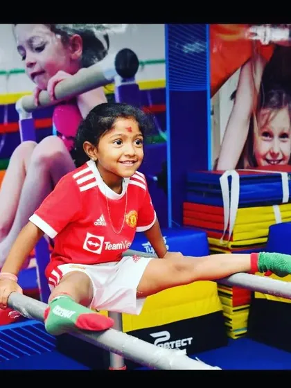 The smile of achievement. We celebrate every milestone, like mastering a split on the parallel bars, which builds not just flexibility but also immense self-confidence and body awareness.