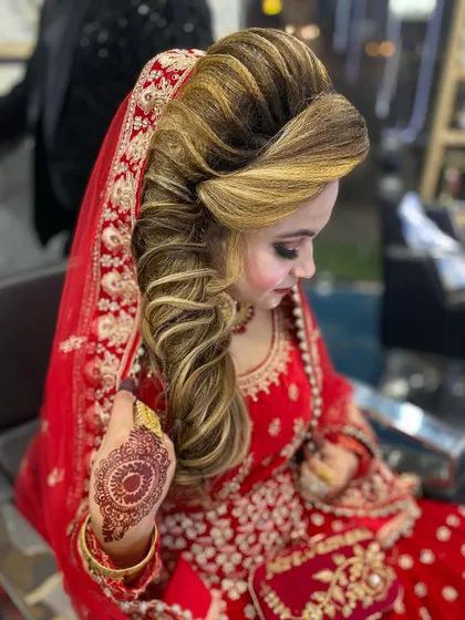 A stunning bridal look for a traditional wedding ceremony. I created this voluminous, side swept hairstyle with highlights to complement the bride's red lehenga and intricate makeup.