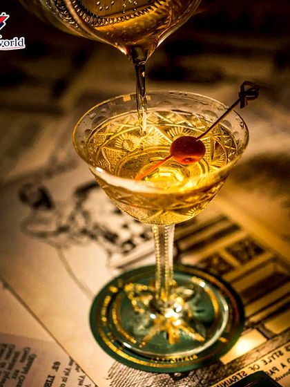 A tasty delight and a visual treat. This vintage-style coupe with a cherry garnish is being filled, capturing a moment of classic cocktail elegance.