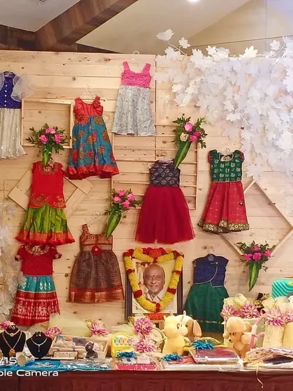 This is a creative display I set up for a naming ceremony, showcasing the baby's new clothes and gifts. The rustic wooden backdrop and decorative elements create a charming and personal corner at the event.