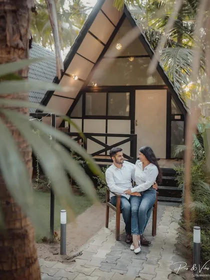 A sweet portrait of the couple sitting together outside their cabin, framed by tropical leaves for a natural, intimate feel.