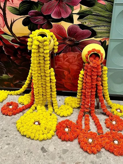 A creative twist on traditional decor. We used marigold flowers to create these unique floor arrangements flowing out of decorated pots.