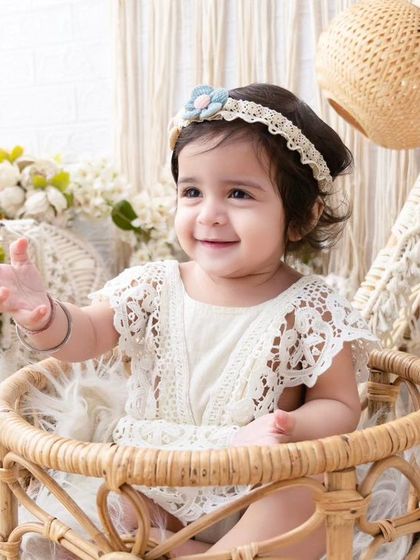 A happy baby girl reaching out. The soft lighting and beautiful boho props create a warm and inviting scene.