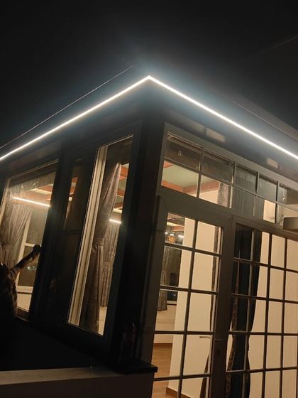 A dramatic night view of a glass pergola with integrated LED lighting. This structure transforms the outdoor space into a usable and striking feature of the home, even after dark.