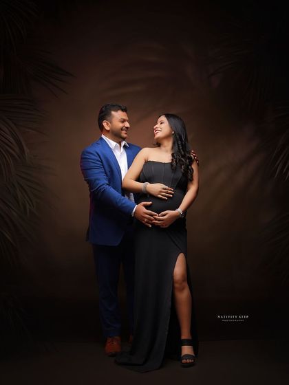 A stylish couple's portrait with a tropical-themed backdrop. The formal attire of the couple contrasts beautifully with the natural elements.