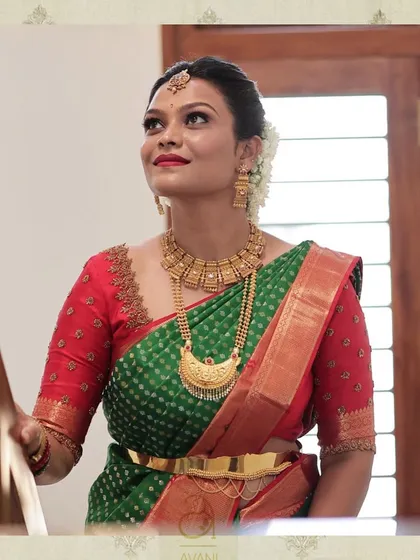 A classic combination of a green and red bandhani saree paired with a custom red blouse. The blouse features simple but elegant embroidery along the neckline.
