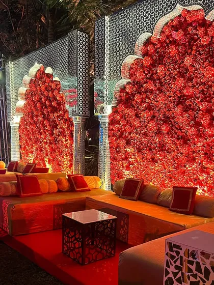 A comfortable and stylish seating area for guests. The combination of red floral walls, traditional arches, and low seating creates a relaxed yet luxurious lounge space.