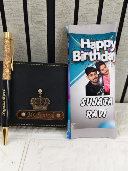 A simple birthday gift set featuring a personalized wallet and pen, along with a chocolate bar customized with a couple's photo and names.