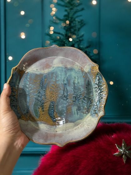 A hand-held view of a large serving plate with a forest-like impression. The reactive glaze creates a beautiful, atmospheric effect, making this a stunning centerpiece for any table.