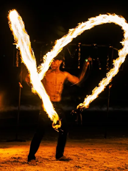 A fire dancer creates a heart of flames on a Phuket beach, capturing the vibrant and exciting nightlife of Thailand.