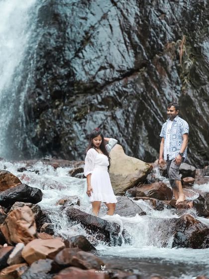 A candid shot of the couple enjoying the waterfall, with the woman stepping through the rushing water. It’s a natural and refreshing moment.