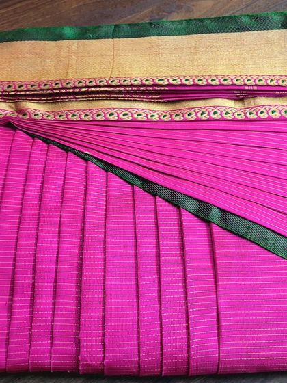 A vibrant pink saree pre-pleated for a client, showcasing the neatness of the box fold.