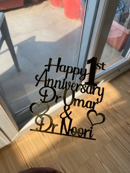 The anniversary topper for the doctor couple seen against a window, creating a silhouette effect that highlights its shape.