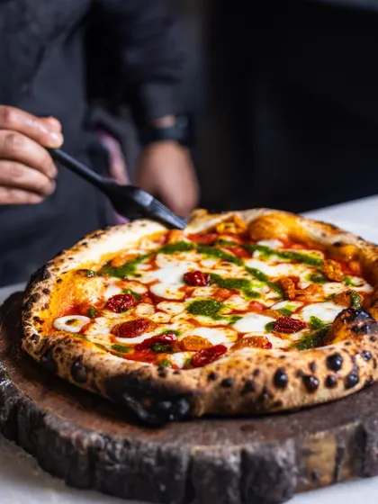 A final brush of pesto adds a fresh, herbaceous finish to this Sundried Tomato pizza, straight from the oven.