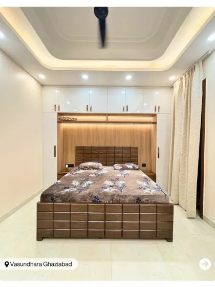A bedroom designed for maximum storage and style. The bed is flanked by full-height wardrobes with a built-in niche above the headboard, all in a clean white and wood finish.