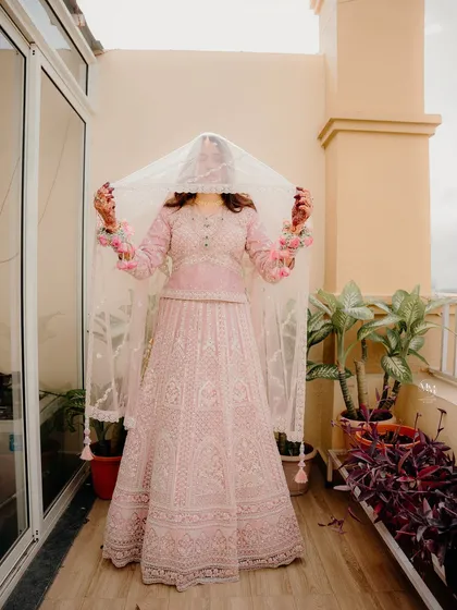A full-length shot of the bride holding her veil. This pose creates a beautiful silhouette and showcases the intricate details of her Nikah outfit.