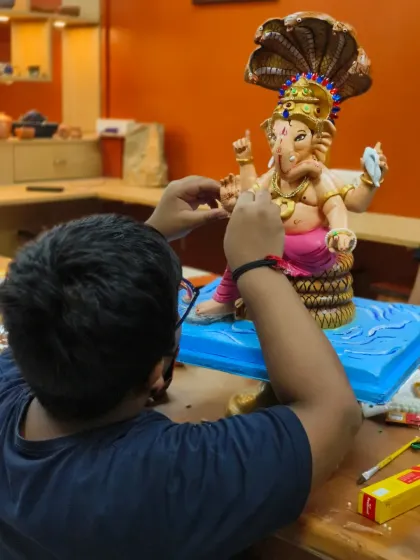 The final touches are what bring a sculpture to life. Here, a student is carefully painting his detailed Ganpati idol, a culmination of two months of patient work and learning advanced sculpting techniques.