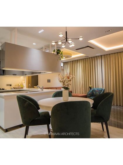 The open kitchen and dining area at Bhagwati Greens. The overhead unit defines the kitchen space without closing it off, maintaining a bright and airy feel.