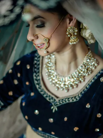 A traditional bridal look with a touch of modern elegance. The focus is on her kundan jewelry, nath, and the soft glam makeup that enhances her features.