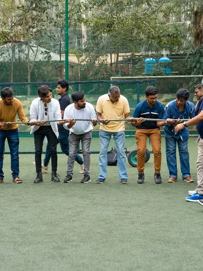 A team works together, holding a long pole in a test of strength and coordination.