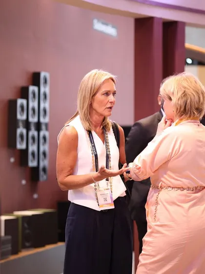 Two international attendees networking amidst a backdrop of high-fidelity audio equipment. The expo is a global meeting point for the AV industry.