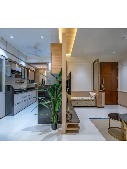 A wide shot of an open-plan layout where the TV unit acts as a subtle divider between the kitchen and living areas.