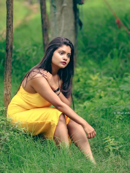 A thoughtful, seated portrait in a green, natural setting. The soft light is perfect for this kind of contemplative shot.