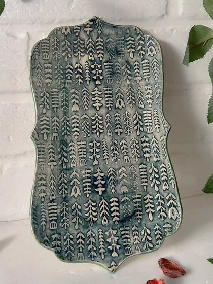 This embossed platter features a pattern of little Christmas trees. It's perfect for serving holiday appetizers or cookies. The design is from a rolling pin.