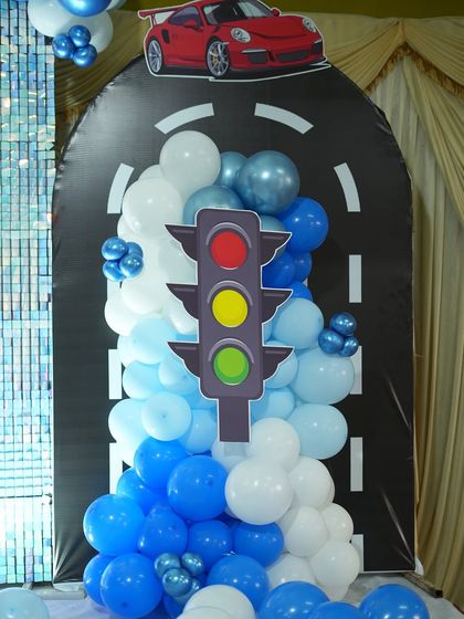 For our car-themed party, we created this fun backdrop with a road design and a traffic light cutout. The balloon cascade looks like it's bursting out from the road.