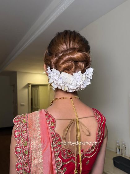 A beautiful braided bun adorned with a row of white flowers, a perfect look for a reception.