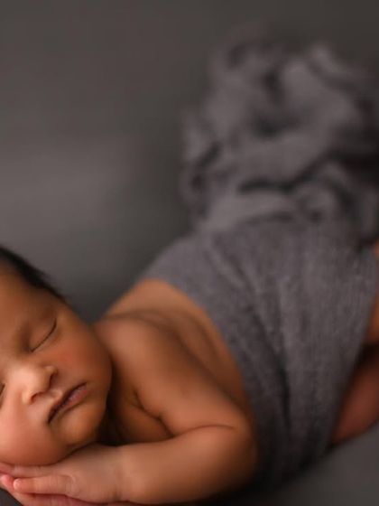 A slightly different angle of the side-laying pose, capturing the baby's full length. These simple, unposed shots are beautiful for highlighting the natural and delicate form of a newborn.