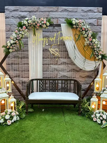 A romantic and rustic photo booth or seating area. The design features a wooden bench, vintage-style lanterns, and soft floral arrangements, with a sign that reads 'Always and Forever' to capture the sentiment of the day.