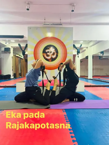 Here, we use straps to assist in the partner Pigeon Pose. Props are our friends, helping us to safely deepen the posture and work on flexibility.