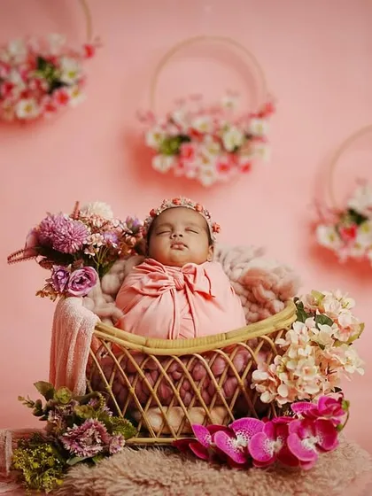 This wider shot shows the full scale of our pink floral theme, with hanging floral hoops in the background that add depth and elegance to the newborn portrait.
