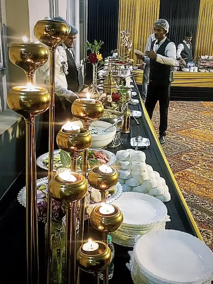 Candlelight adds a touch of warmth and sophistication to any buffet. This setup features elegant candle stands alongside a delicious spread, creating a cozy and inviting ambiance for guests.
