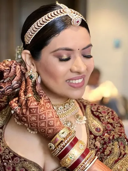 A candid moment of a bride getting ready, her hair in a beautiful floral bun. This updo is a classic choice that never goes out of style.