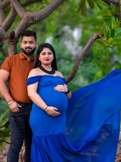 A beautiful outdoor couple portrait. The mom to be looks stunning in her blue gown, and her partner stands proudly by her side, creating a lovely family picture.
