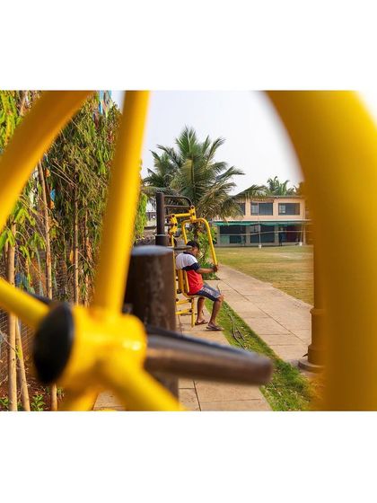 Outdoor fitness equipment, integrated into the landscape, provides an opportunity for residents to exercise in the open air. This view through a piece of equipment frames the park, highlighting its role in promoting community health and wellness.