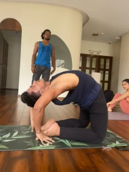 A student receives an adjustment in Ustrasana during a workshop. These sessions provide focused attention on complex poses, helping practitioners refine their technique.