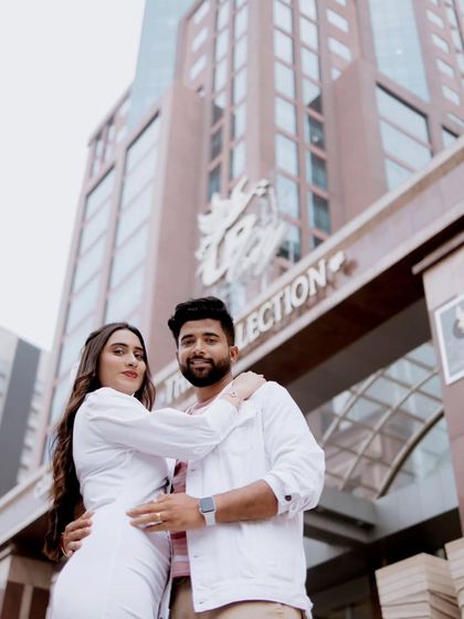 A low-angle shot of a couple posing in front of a modern building, giving a powerful and stylish feel to their urban pre-wedding photo.